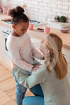 Cute curly daughter hugging her caring loving mother