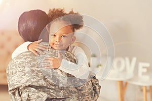 Cute curly girl hugging her mother in military uniform