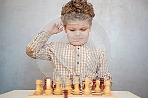 Cute curly-haired boy playing chess