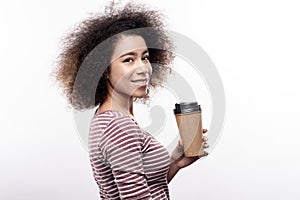 Cute curly-haired young woman holding coffee cup