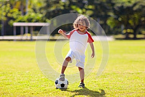 Cute curly little boy playing football. Kids play