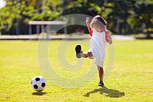 Cute curly little boy playing football. Kids play