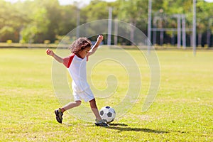 Cute curly little boy playing football. Kids play