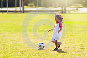 Cute curly little boy playing football. Kids play