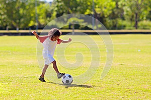 Cute curly little boy playing football. Kids play