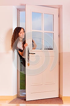 Cute curly teenage girl opening the front door