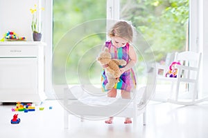 Cute curly toddler girl playing with her teddy bear