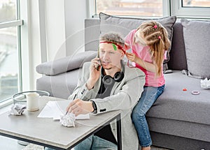 Cute daughter decorating teleworking father photo