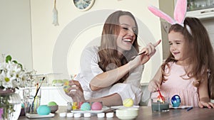 Cute daughter with mommy preparing for easter and painting eggs.