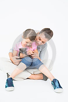 Cute daughter and mother sitting with pet kitten together