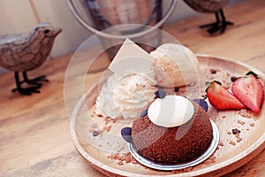 Cute and delicious brown bear cake served with strawberry, vanilla ice cream and whipped cream in wooden plate.