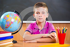 Cute diligent boy sitting in classroom