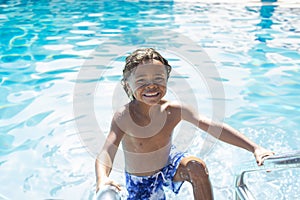 Cute Diverse little boy climbing out of a swimming pool on a warm summer day