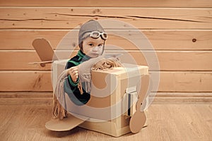 Cute dreamer boy playing with a cardboard airplane.