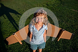 Cute dreamer boy playing with a cardboard airplane. Childhood. Fantasy, kids imagination.