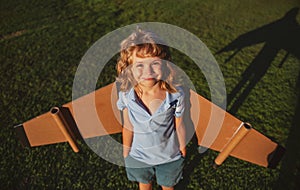 Cute dreamer boy playing with a cardboard airplane. Childhood. Fantasy, kids imagination.