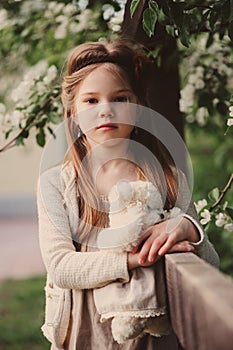 Cute dreamy child girl posing at rustic wooden fence with teddy bear