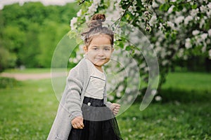 Cute dreamy toddler child girl walking in blooming spring garden