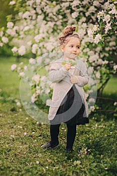 Cute dreamy toddler child girl walking in blooming spring garden