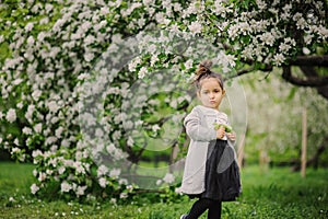 Cute dreamy toddler child girl walking in blooming spring garden