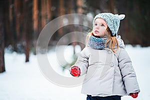 Cute dreamy toddler girl walking in winter forest