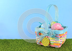 Cute Easter image with green grass and blue sky with colorful easter basket full of sparkly eggs.