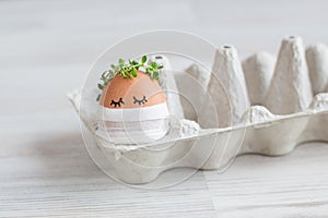 Cute egg with eyes, a flower wreath, in a medical mask celebrates Easter alone