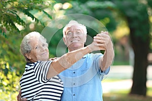 Cute elderly couple dancing outdoors.