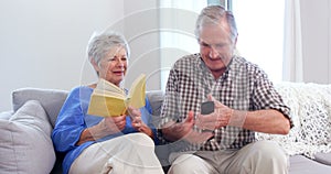 Cute elderly couple reading or watching TV