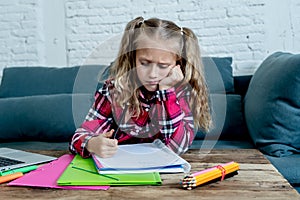 Cute elementary student feeling sad and confusing while doing difficult assignment with her laptop at home in primary school