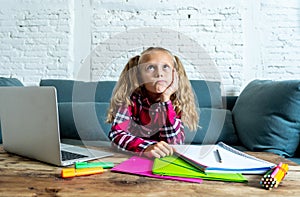 Cute elementary student feeling sad and confusing while doing difficult assignment with her laptop at home in primary school