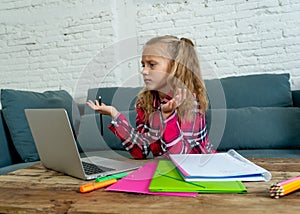 Cute elementary student feeling sad and confusing while doing difficult assignment with her laptop at home in primary school