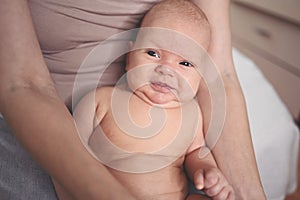 Cute emotional funny smiling newborn little baby infant boy sitting on mother hands. Healthy child