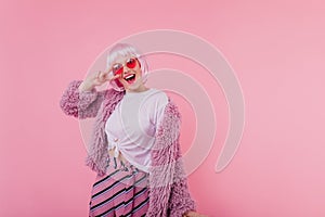 Cute emotional lady in pink short periwig fooling around in studio. Photo of happy european female