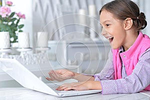 Portrait of cute little girl using modern laptop