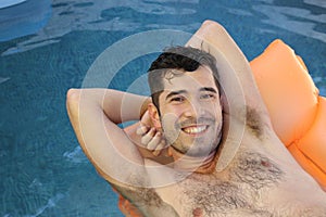 Cute ethnic man sunbathing in swimming pool