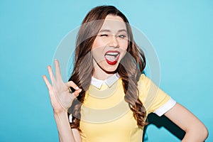 Cute excited girl in dress showing ok gesture and winking