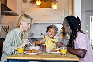 Cute family having breakfast together, enjoy meal at home in kitchen, in the morning