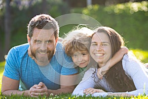 Cute family portrait hugging and embracing. Family lying on grass in park. Parents and children on vacation playing