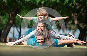 Cute family portrait. Portrait of a happy smiling family relaxing in park. Family lying on grass in park. Fly concept