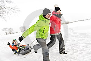 Cute Family Pulling Sledge Through Snowy Landscape