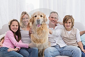 Cute family relaxing together on the couch with their dog