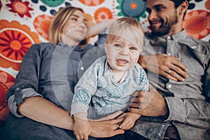 Cute family resting on boho hammock with crying baby boy, sad child with parents face close-up