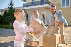 Cute family unpacking cardboard boxes while moving to a new house