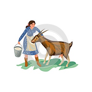 Cute farmer woman in blue dress is feed goat
