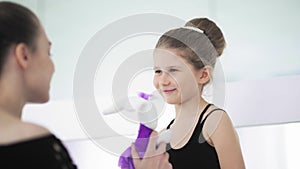 Cute Female ballet teacher gives his sad student a toy to calm her