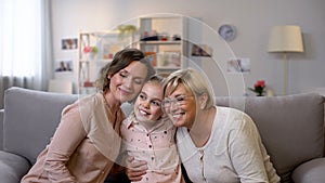 Cute female family embracing, sitting on sofa at home, trustful relationship