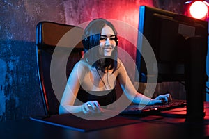 A cute female gamer girl sits in a cozy room behind a computer and plays games. Woman live streaming computer video