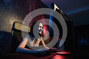 A cute female gamer girl sits in a cozy room behind a computer and plays games. Woman live streaming computer video