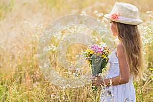 Cute female kid with flowers on meadow